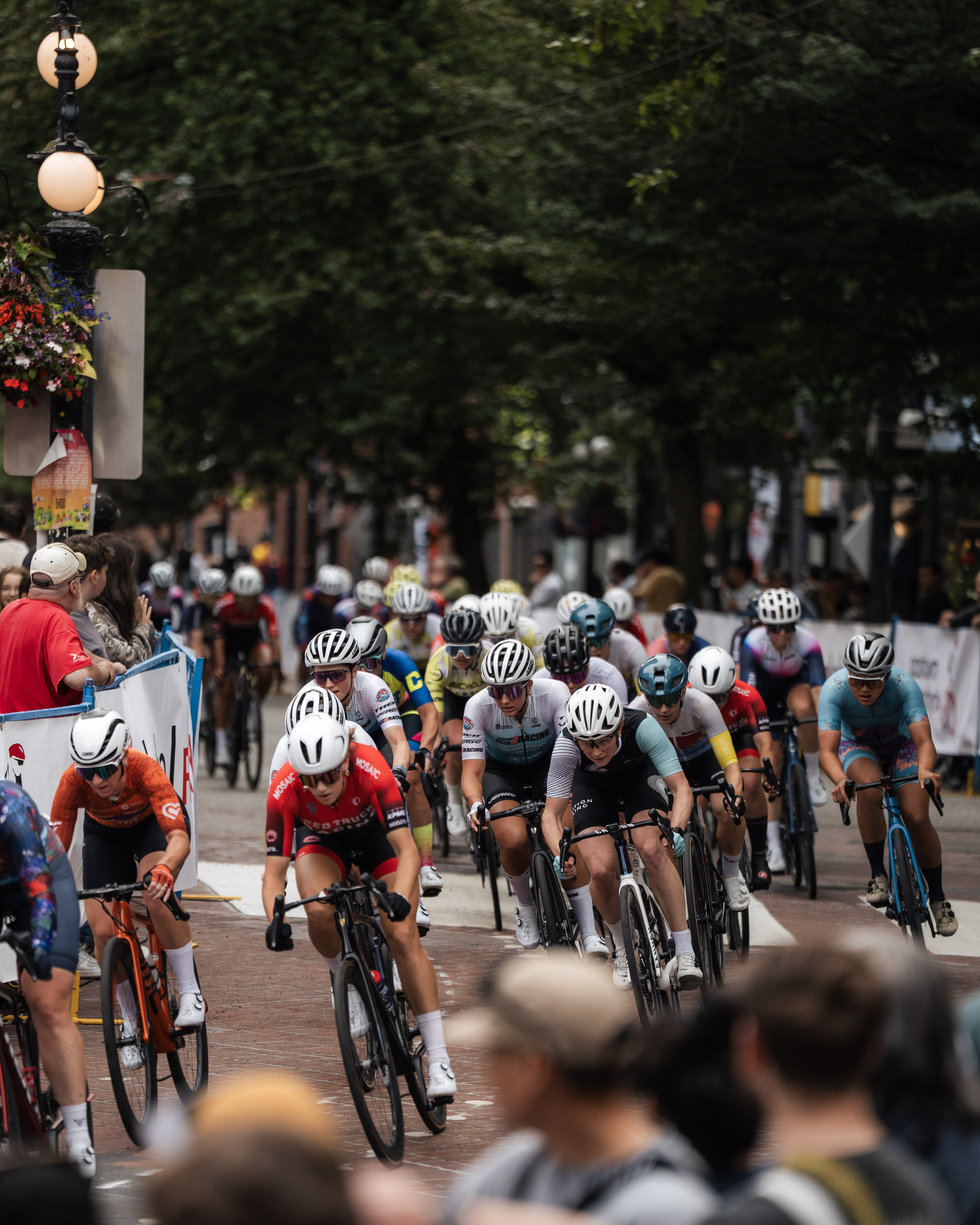 Group of cyclists racing on a city street with spectators watching from the sidelines.