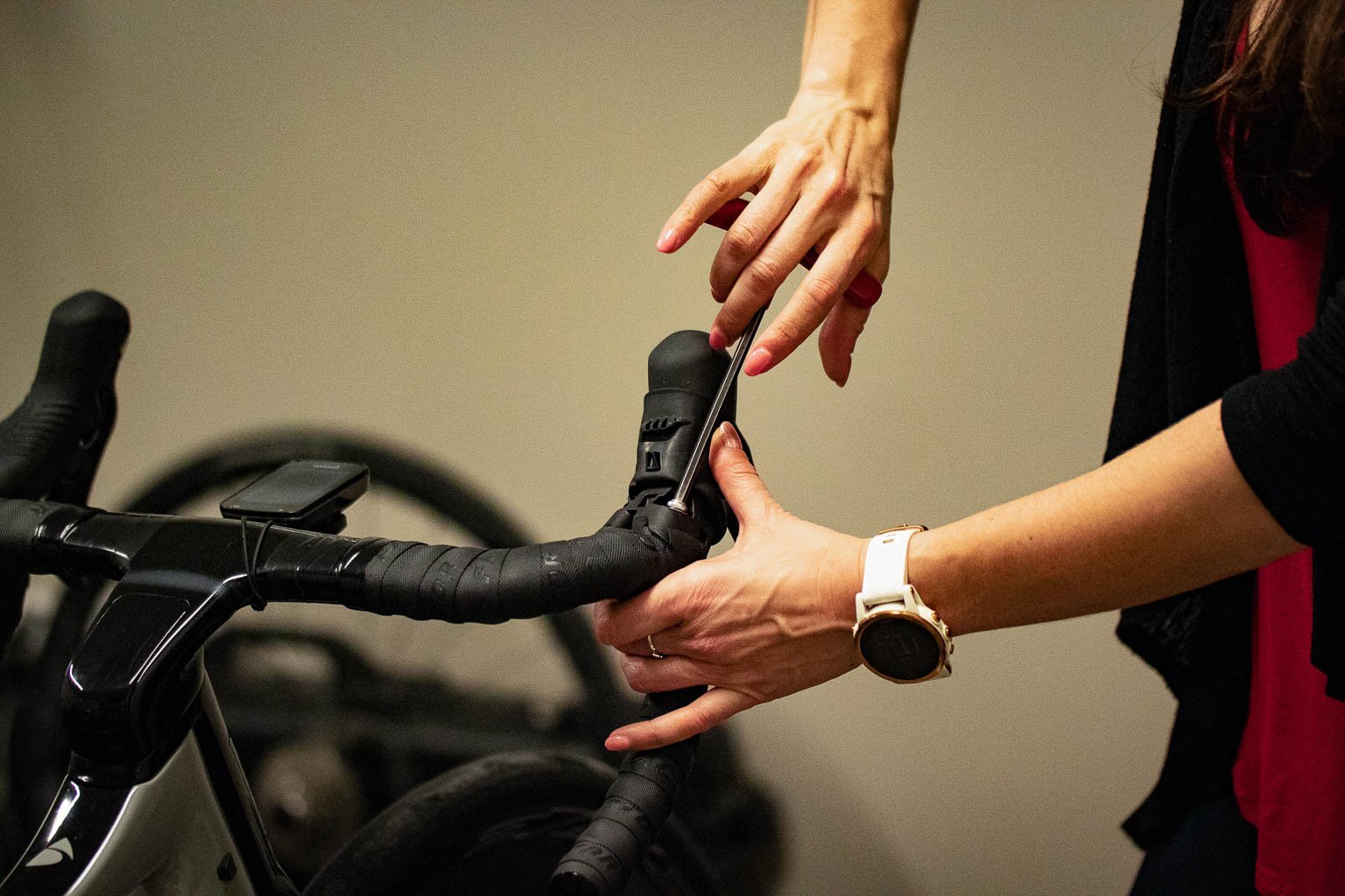 Person using a screwdriver to adjust the brake lever on a black road bike handlebar.